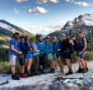 A smiling group of friends wearing backpacking backpacks, hiking in the Trinity Alps mountains of northern California